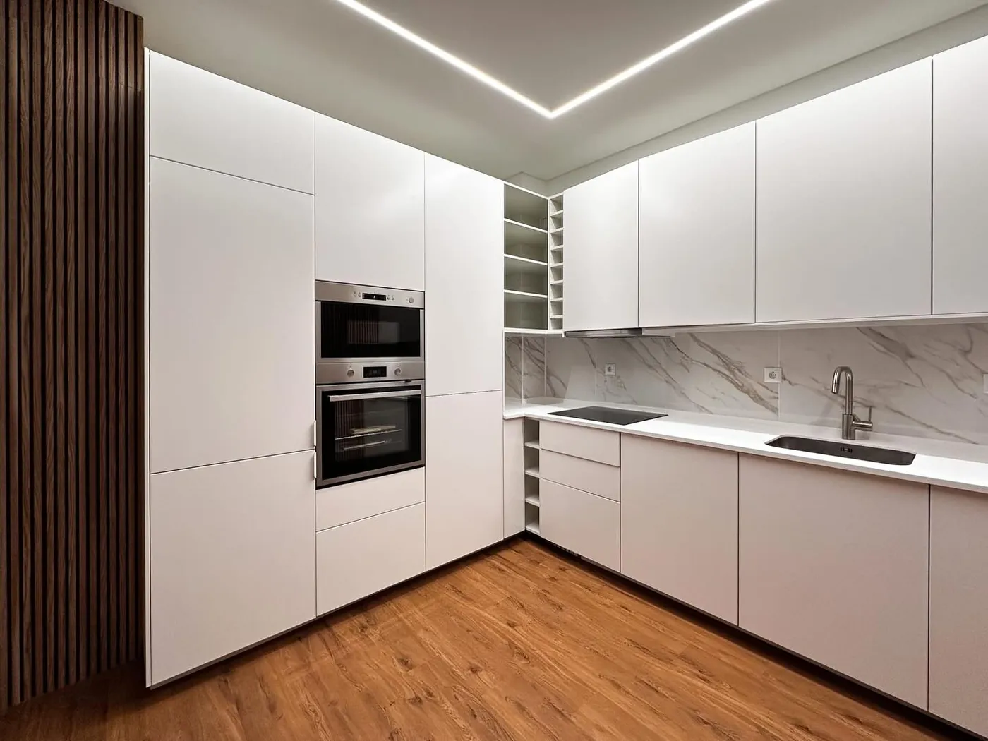Cocina blanca integrada con revestimientos de madera realizada por SC Interior